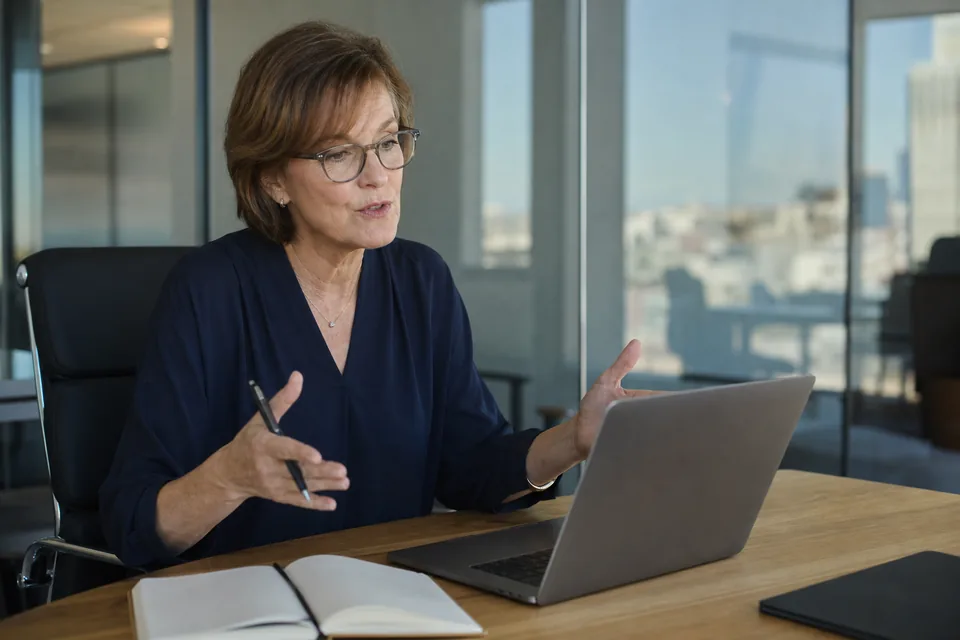 Executive search partner on a client video call in a small glass-walled office
